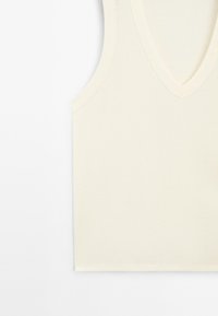 V-ringad, ärmlös topp i krämfärg, tillverkad av ett mjukt, något stretchigt material. Har en ren, minimalistisk design utan synliga mönster eller detaljer.