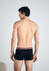 Boxeri negri cu talie roz. Talia prezintă numele mărcii "HUGO" în roșu. Material moale, design minimalist și formă ajustată.