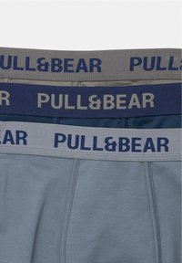Dva para bokserica u sivoj i mornarskoj boji, s elastičnim pojasima na kojima se nalazi logo "PULL&BEAR" u kontrastnim bojama. Glatka tekstura tkanine.