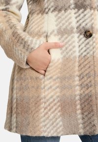 Wollmischungsjacke in einem tan- und cremefarbenen Karomuster, mit einem einzelnen braunen Knopf und Seitentaschen, und einer weichen, strukturierten Oberfläche.