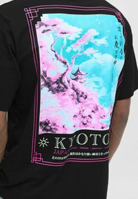 Sort bomulds T-shirt med et farverigt grafik af kirsebærtræer, en pagode, og "KYOTO" tekst i hvid og lyserød.