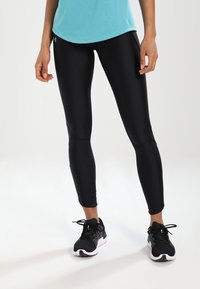 Svarta sportleggings i stretchmaterial med en slimmad passform, kombinerade med en turkos topp och svarta löparskor.