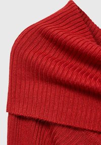 Röd ribbad tyg med en texturerad yta, med vertikala linjer och en vikning högst upp. Mjuk, elastisk material.