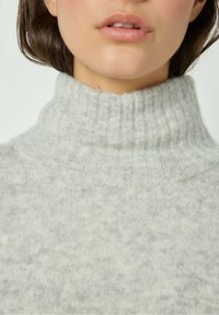 Maglione grigio a coste con collo alto e una texture morbida; presenta un motivo sottile che mescola tonalità di grigio chiaro e scuro.