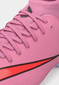 Rosa fotballsko med en glatt syntetisk overdel og tonede lisser. Har en iøynefallende rød swoosh-logo langs siden og en subtil svart detalj.