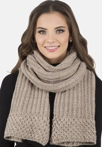 Sciarpa beige lavorata a maglia con texture a coste e motivo a treccia alle estremità, spessa e avvolta attorno al collo.