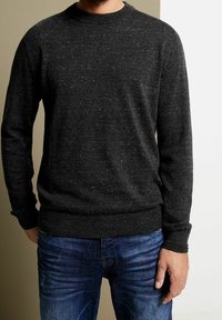 Tmavě šedý pletený svetr s kulatým výstřihem a dlouhými rukávy, který má jemnou skvrnitou texturu a žebrované lemy na rukávech a spodním okraji.