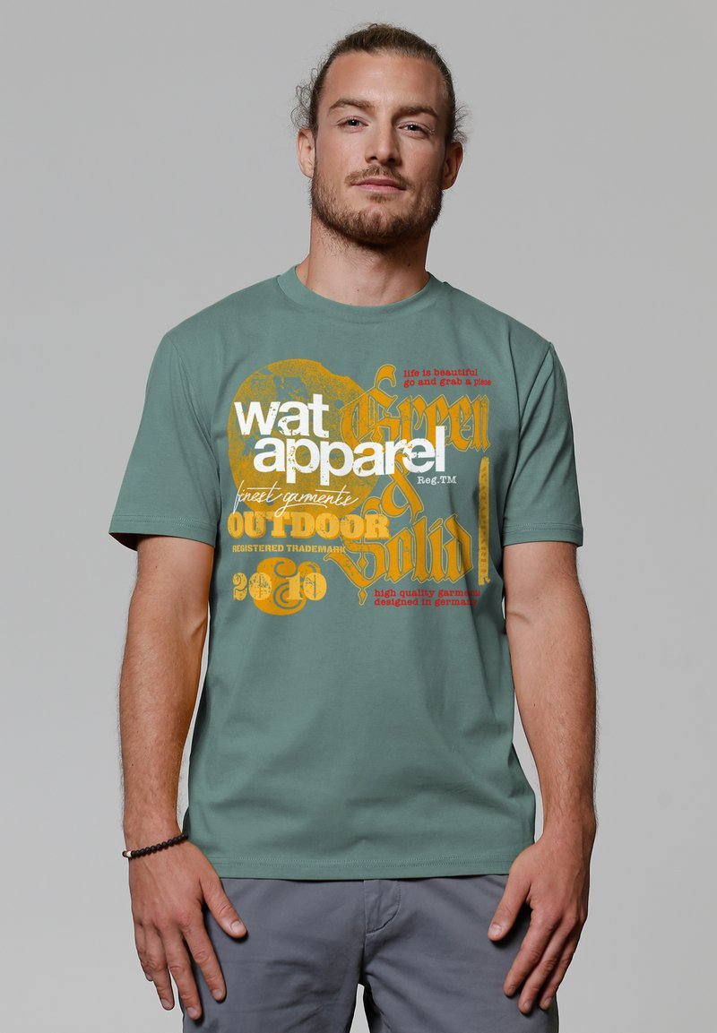 Grünes Baumwoll-T-Shirt mit auffälligem gelb-orangefarbenem Grafiktext, kurzen Ärmeln und rundem Ausschnitt. Deutlich sichtbares Branding.