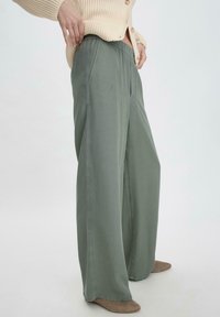 Lichtgroene wijde broek met een elastische tailleband, gemaakt van een zachte stof, met voorzakken en een ontspannen silhouette.