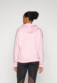 Ljusrosa sweatshirt med huva, med en avslappnad passform och ribbade muddar. Bärs med svarta leggings som har en genomskinlig paneldesign.