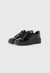 Zapatillas de piel sintética negra con suela gruesa negra, que presentan detalles en dorado y un diseño texturizado en la parte superior.