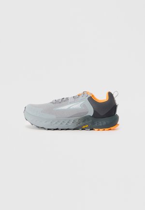 Lys grå atletisk sko med mesh-overdel, orange accenter og en textured mørkegrå hæl. Har en robust ydersål med Vibram-branding.