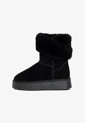 Black suede ankle boot with a fold-over faux fur collar, flat rubber sole, and contrasting stitching details. Smooth texture, rounded toe design.
