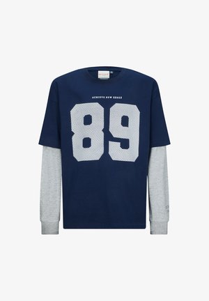 T-shirt blu navy con maniche lunghe grigie, con numeri perforati bianchi "89" e la scritta "ACHIEVE NEW GOALS" sopra in un font contrastante.