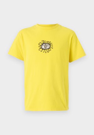 Geel katoenen t-shirt met een zwarte graphic van een oog met draaiende lijnen erboven en eronder. Korte mouwen en een ronde hals.