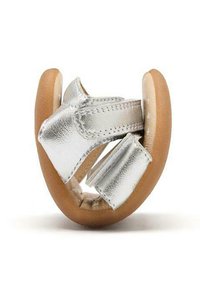 Calzado de cuero plateado con una suela suave y redondeada, y múltiples correas para un ajuste seguro. Presenta una textura lisa y un diseño minimalista.