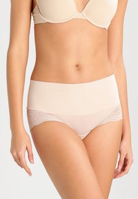 Beige korkeavyötäröiset alushousut, joissa on sileä etupaneeli ja läpikuultavat pitsisivut, joissa on herkkiä kukkakuvioita reunojen ympärillä.