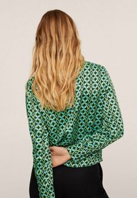 Grüne gemusterte Bluse mit geometrischen Formen, langen Ärmeln, cropped Schnitt und glattem, glänzendem Stoff.
