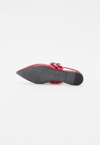 Scarpa rossa a punta con sopracchi in pelle liscia, dettagli a doppio cinturino e suola in gomma nera con scanalature di trazione.