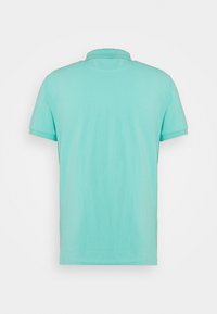 Polo en coton vert menthe clair, à manches courtes, avec un col et une coupe décontractée. Texture lisse, sans motifs ni logos visibles.