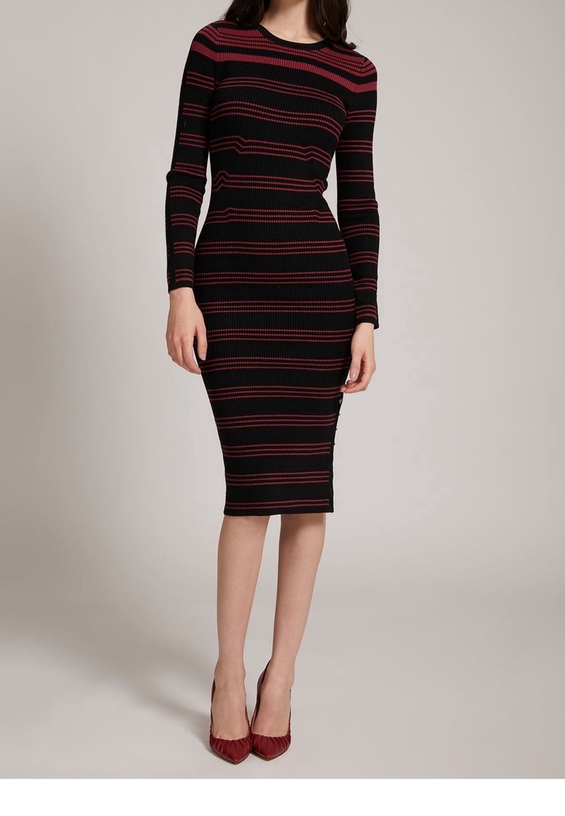 Robe midi noire à côtes avec des manches longues, ornée de rayures horizontales rouges, de coupe ajustée, avec un col rond et un ourlet droit. Assortie à des talons aiguilles rouges.
