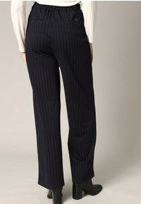 Marineblauwe pinstripe broek met een relaxed fit, elastische tailleband en twee achterzakken. Gecombineerd met zwarte haklaarzen.