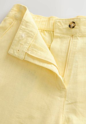 Lysegule linnedbukser med en flad taljebånd, en knappelukning og en skjult lynlås. Har en subtil tekstur og pæn syning.