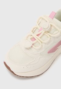 Baskets beiges avec tige en mesh et accents en suede. Présentent des détails roses et un système de lacets à tirette. Semelle texturée pour une meilleure adhérence.