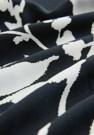 Melna auduma ar baltu ziedu rakstu, kas izceļas ar gludu tekstūru un plūstošu izskatu, uzsverot krāsu kontrastus.