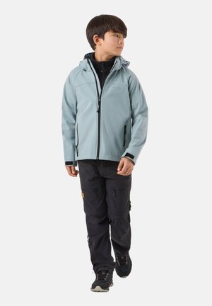 Junge, der geht und eine hellblaue Kapuzenjacke, schwarze Cargohosen und schwarze Wanderschuhe trägt, schaut nach rechts.