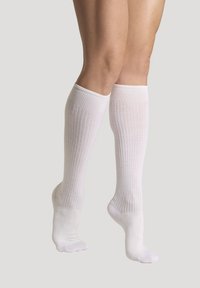 Knähöga vita strumpor med ribbad textur, slät yta och förstärkta tån och häl. Lämpliga för olika skostilar.