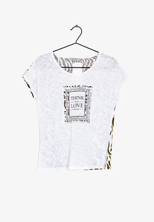 Top blanco de manga corta con un estampado gráfico en blanco y negro en el centro, enmarcado por un borde con patrón de cebra a los lados.