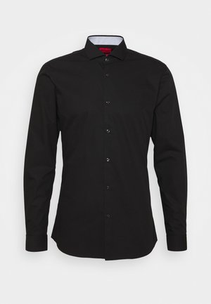 Czarna długa koszula męska na guziki z klasycznym kołnierzem i widocznymi przednimi guzikami, przedstawiona na jednolitym jasnoszarym tle.