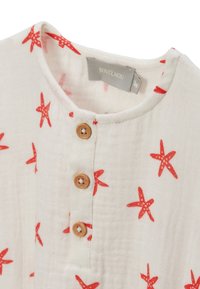 Chemise blanche avec des motifs d'étoiles de mer rouges, encolure ronde et trois boutons en bois. Tissu doux et texturé. Étiquette de marque visible à l'intérieur.
