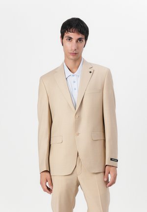 Beige Anzug mit einreihigem Sakko und zwei Knöpfen. Passende Hose, hellblaues Polohemd darunter, minimalistisches Design mit Taschenakzent.