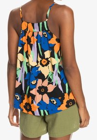 Top sans manches à motif floral avec un dos froncé. Présente des couleurs vives : bleu, orange, noir et vert. Assortie à un short olive.