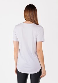Camiseta blanca de manga corta con dobladillo redondeado. Tejido suave, costuras mínimas y escote redondo. Sin patrones ni acentos notables.