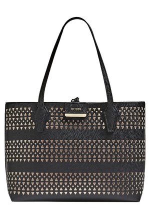 Schwarze Guess Tote-Tasche mit doppelten Griffen und horizontalen Reihen ausgeschnittener Dreiecksmuster, die metallisches Gold darunter sichtbar machen.