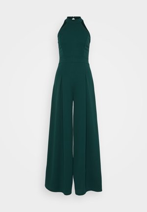 Donkergroene mouwloze jumpsuit met hoge halslijn, brede benen, plooien en een stevige stofstructuur. Geen zichtbare hardwaredetails.