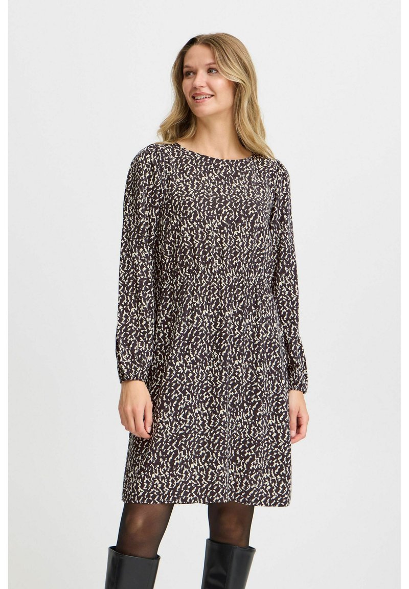 Braun gemustertes Kleid mit langen Ärmeln, das einen runden Hals und eine lockere Passform aufweist. Kombiniert mit kniehohen schwarzen Stiefeln, die mit kontrastierenden Texturen spielen.