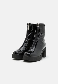Cizme negre din piele lucioasă, până la gleznă, cu două fermoare, vârf pătrat și toc gros, texturat. Design elegant cu un finisaj strălucitor.