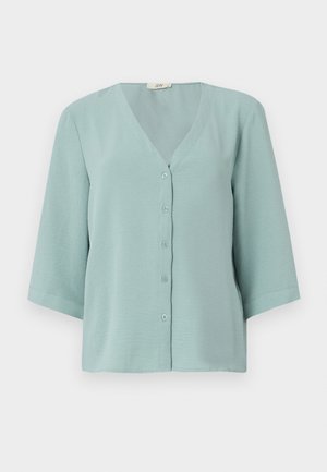 Blouse bleu-vert clair à manches trois quarts et décolleté en V. Fabriquée à partir d'un tissu doux et léger, avec une texture lisse.