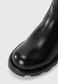 Black leather ankle boot with a rounded toe, smooth texture, thick rubber sole, and subtle stitching details along the side.