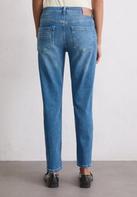 Denim jeans in medium blue, met een recht modellen, subtiele vervaging, twee achterzakken en een bruine label op de tailleband.