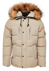 Chaqueta acolchada beige con capucha de piel desmontable, dos bolsillos en el pecho, detalles en negro y cierre con cordón alrededor del cuello y el dobladillo.