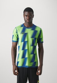 Green and blue short-sleeve sports shirt featuring a zigzag pattern and an Adidas logo on the upper left side. Textured fabric finish.