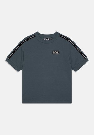 T-shirt grigio a maniche corte realizzato in cotone. Presenta dettagli neri lungo le spalle e un piccolo patch con logo sulla parte anteriore. Design classico con scollatura a girocollo.