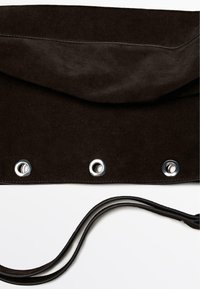 Borsa a tracolla in suede marrone con patta superiore, occhielli in argento e tracolla piatta. Texture liscia con dettagli di cucitura a contrasto.