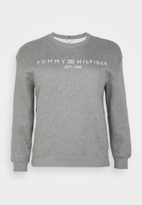 Sudadera gris de cuello redondo hecha de una mezcla de algodón. Presenta un logo impreso en blanco "TOMMY HILFIGER EST. 1985" en la parte frontal. Mangas largas y puños acanalados.