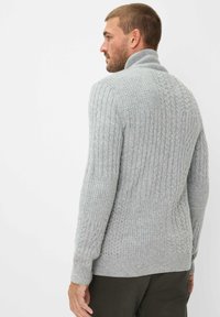 Hellgrauer gestrickter Pullover mit hohem, umgeschlagenem Kragen. Hat strukturierte Zopfmuster und gerippte Bündchen. Figurbetonter Schnitt, mittlere Dicke.